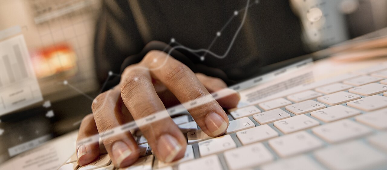 Hände tippen auf einer Tastatur, überlagert von Datenlinien
