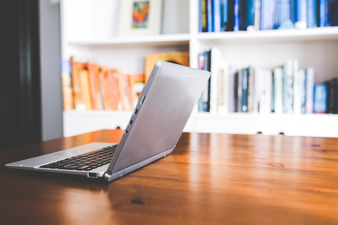 Ein Laptop auf einem Schreibtisch vor einem Bücherregal